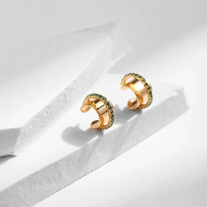 Gros plan détaillé des manchettes d'oreille en C avec zircons verts sur fond de pierre