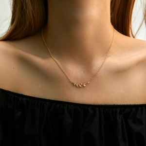 Collana dorata con pendente a foglia e zirconi bianchi indossata da una modella
