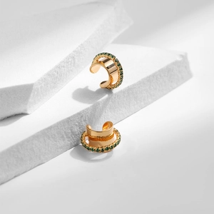 Détail de boucles d'oreilles dorées avec pierres zircons verts sur socles blancs