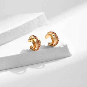 Détail d'un ear cuff doré au design triple couche avec des pierres de zircon orange