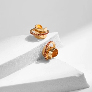 Gros plan détaillé des ear cuffs dorés sertis de zircons jaunes sur des blocs géométriques