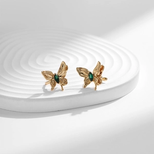 Détail d'un ear cuff papillon doré avec pierre marquise verte et ailes ciselées