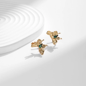 Boucles d'oreilles papillon en or 18K avec zircon vert sur un support blanc élégant