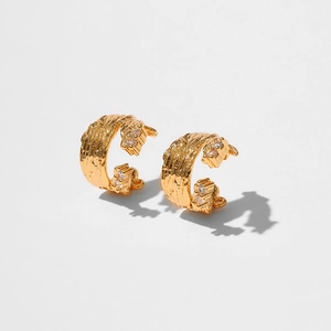 Detailed close-up of golden textured ear cuffs with zircon stones and hammered finish