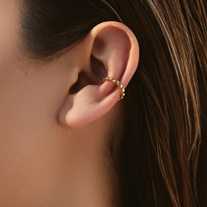 Vue détaillée d'une manchette d'oreille dorée torsadée avec zircons sur un mannequin