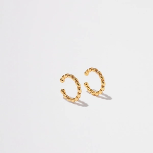 Macro shot of gold-plated ear cuff with twisted rope texture and polished finish