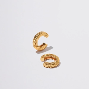 Macro detail of gold-plated butterfly ear cuff featuring delicate twisted metal textures