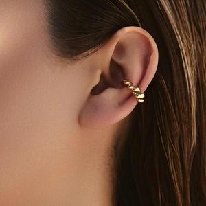 Détail d'un ear cuff doré torsadé sur un mannequin avec une finition brillante polie