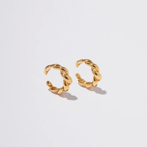 Macro detail of twisted golden ear cuffs showing polished metallic texture and spiral design
