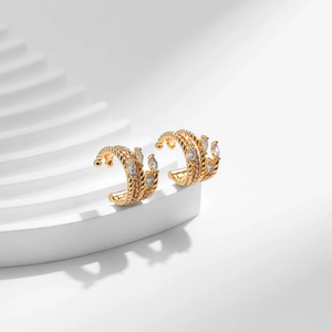 Detail of bohemian gold C-shape ear cuff with twisted texture and marquise zircons