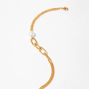 Détail d'un bracelet doré 18K avec grande perle blanche et anneaux entrelacés