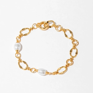 Détail d'un bracelet plaqué or 18K avec perles et texture métallique martelée