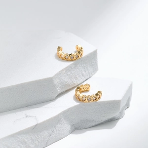 C-shaped 18K gold-plated cuff earrings with honeycomb hexagon zircon stones on marble slab