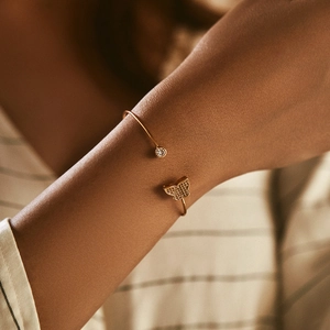 Golden open bangle featuring a sparkling butterfly motif and round cubic zirconia stone