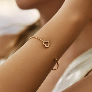 Detail of 18K gold-plated cuff featuring hollow heart with pavé zircons and a round solitaire
