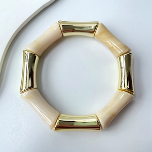 Detail eines klobigen Bambus-Armbands mit Goldmetall und cremefarbenen Harzsegmenten