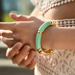 Close-up of mint green bamboo-style beaded elastic bracelet with gold spacer beads on wrist