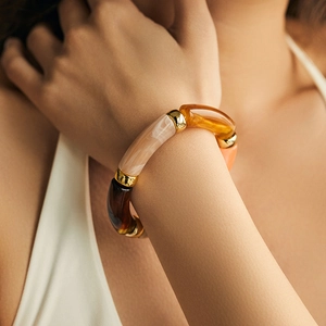 Close-up of chunky resin bangle with amber marble tubes and gold metal accents