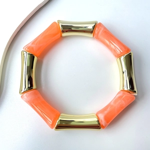 Nahaufnahme des orangefarbenen Marmorharzes und der goldenen Rohre am Bambusarmband