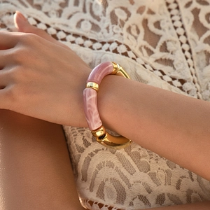 Détails des segments en résine rose et maillons en métal doré sur un bracelet élégant