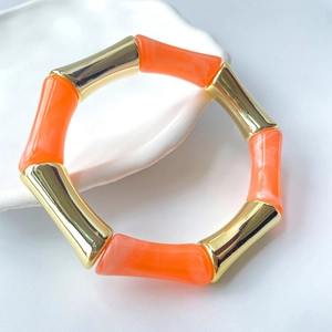 Detail eines Armbands im Bambus-Design mit poliertem Goldmetall und orangefarbenem Harz