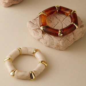 Detail of amber tortoiseshell and ivory marble acrylic bracelets with gold metal accents