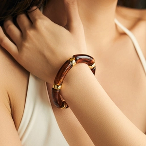 Detailed close-up of tortoise shell resin bracelet with gold metallic spacers on wrist