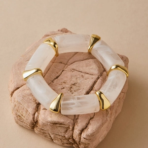 Macro detail of amber resin bracelet with white marble texture and gold triangular spacers