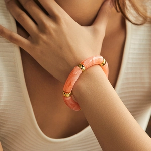 Macro detail of acrylic resin bracelet with orange marble beads and gold metal spacers