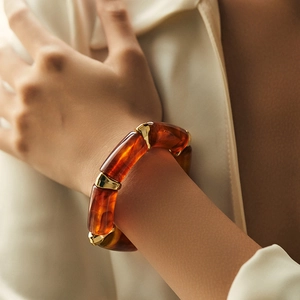 Detail of amber marble resin bracelet with gold-polished metal links on wrist