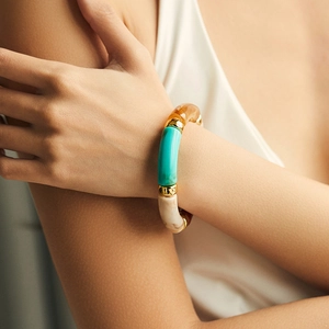 Detail of bamboo-style acrylic bracelet with amber and marble texture on model's wrist