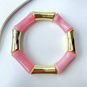 Detailansicht der rosa Harzsegmente und goldener Spiegelröhren an einem Armband