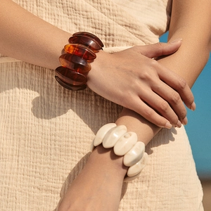 Detail van crème en amber acryl chunky armbanden met bloembladstructuur op model