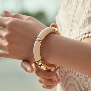 Close-up of mixed cream resin and polished gold metal segments on a chunky elastic bracelet