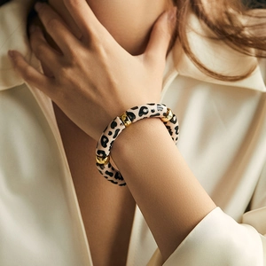 Detail of leopard print acrylic bracelet with gold accents on model's wrist