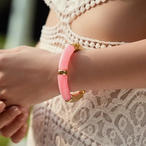 Détail d'un bracelet en résine rose et métal doré avec design de bambou au poignet
