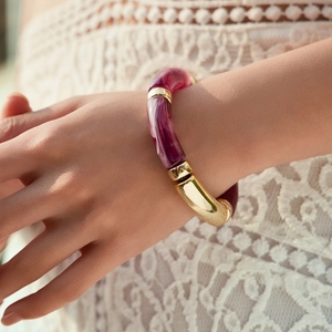 Detail of purple marble resin beads and gold metal tubes on a handmade stretch bracelet
