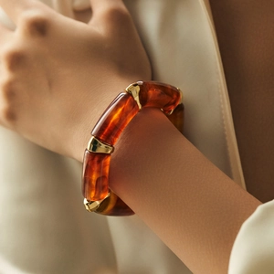 Amber acrylic marble resin bracelet with gold metal accents on a wrist with white suit