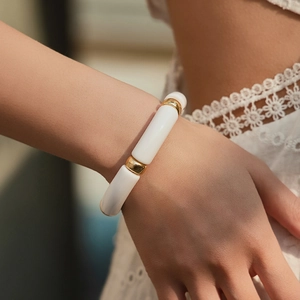 Detail of white tubular beads and gold metal spacers on bohemian elastic bracelet