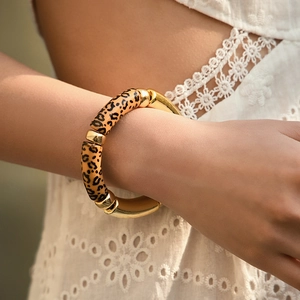 Detail view of bohemian beaded bracelet featuring leopard print and gold metal tubes on wrist