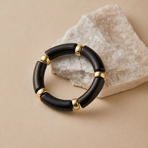 Detail of bohemian acrylic tube bracelet with black gloss and gold metal beads