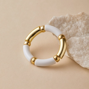 Detailed shot of handmade gold and white enamel beaded stretch bracelet on a stone background