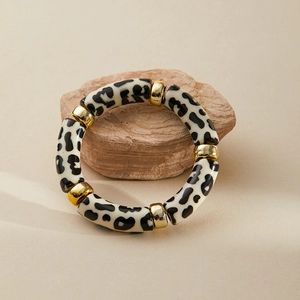 Macro shot of chunky leopard print acrylic bracelet on a stone with gold spacers