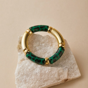 Detail of bohemian gold tube and green leopard resin segments on an elastic bracelet