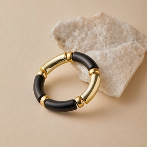 Close-up of black and gold resin bamboo style stretch bracelets on natural stone