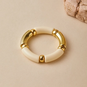 Detail of bamboo-style elastic bracelet with gold metal and beige glossy resin beads