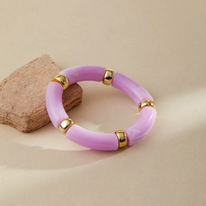 Close-up of lilac marble acrylic bangle with polished gold beads on beige stone surface