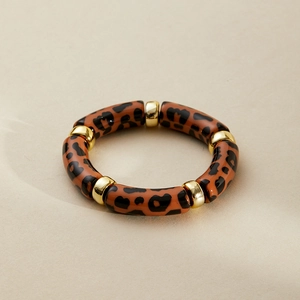 Macro detail of acrylic leopard print tube bracelet with gold metal ring accents