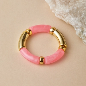 Detail of pink marble acrylic resin tubes and gold metal beads on a beaded bracelet
