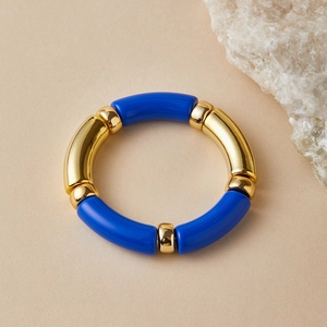 Close-up of a stretch tube bracelet with dark blue resin and polished gold metal accents